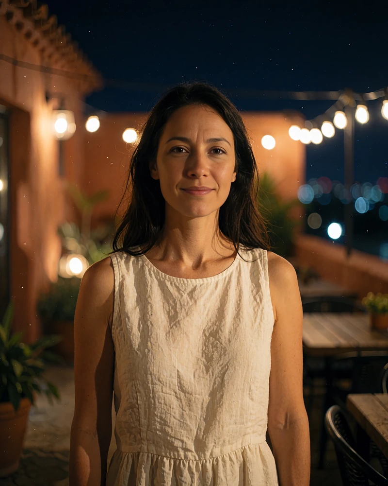Woman with long dark hair in an ivory dress smiling on a warm-lit terrace in San Antonio